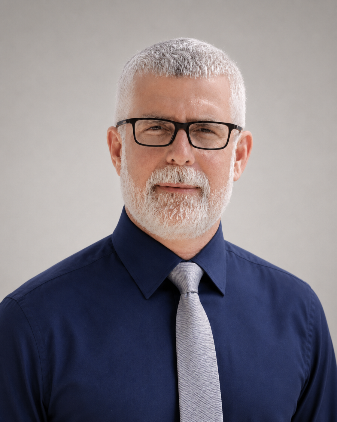 Christopher L. Bray, MD, PhD — in a navy dress shirt and tie with dark-rimmed glasses.